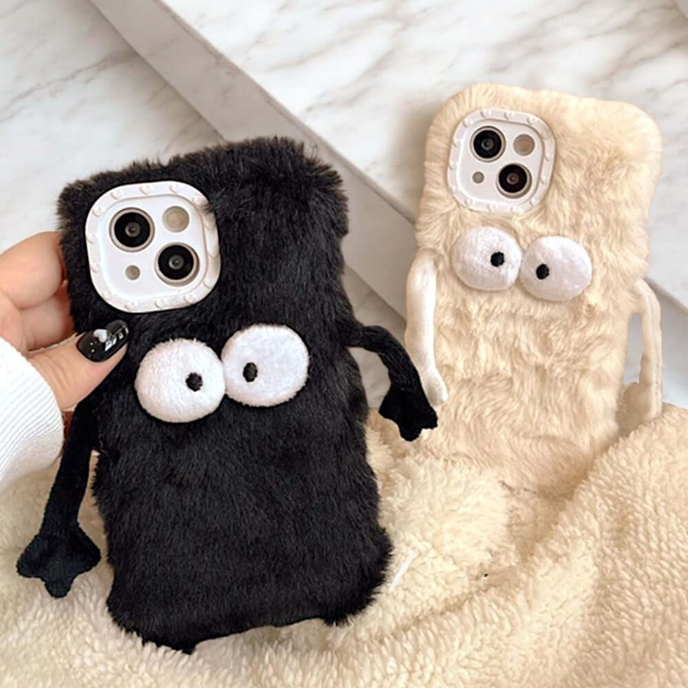 a hand holding a cell phone case with two eyes