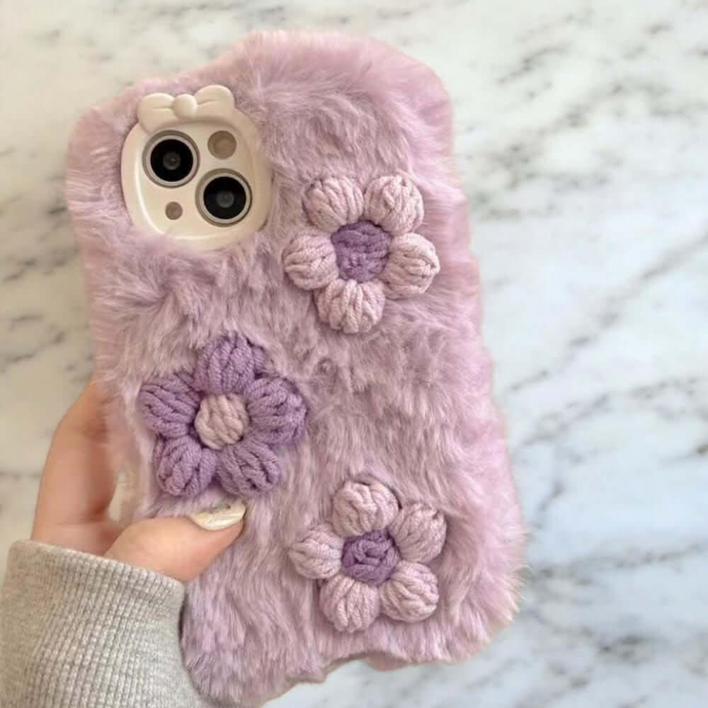 a person holding a cell phone case with crocheted flowers on it