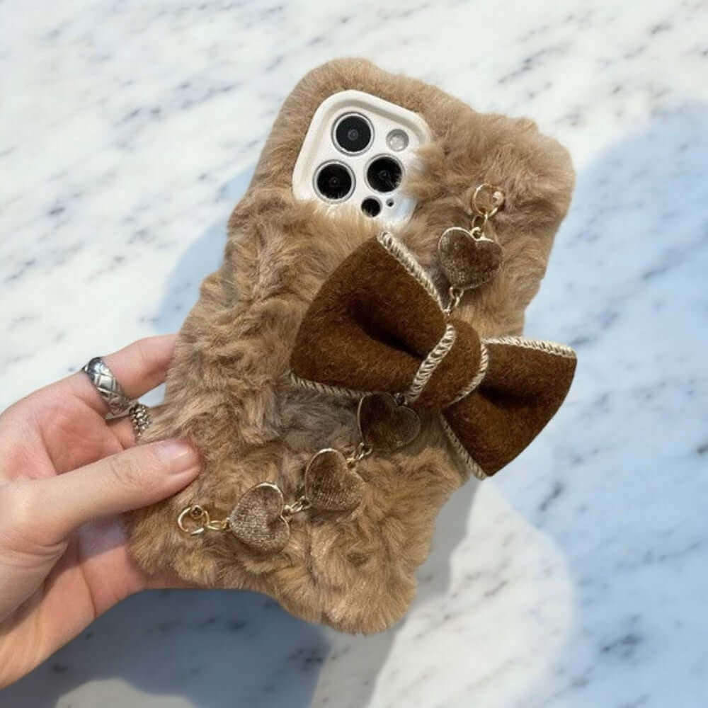 a person holding a cell phone case with a bow on it