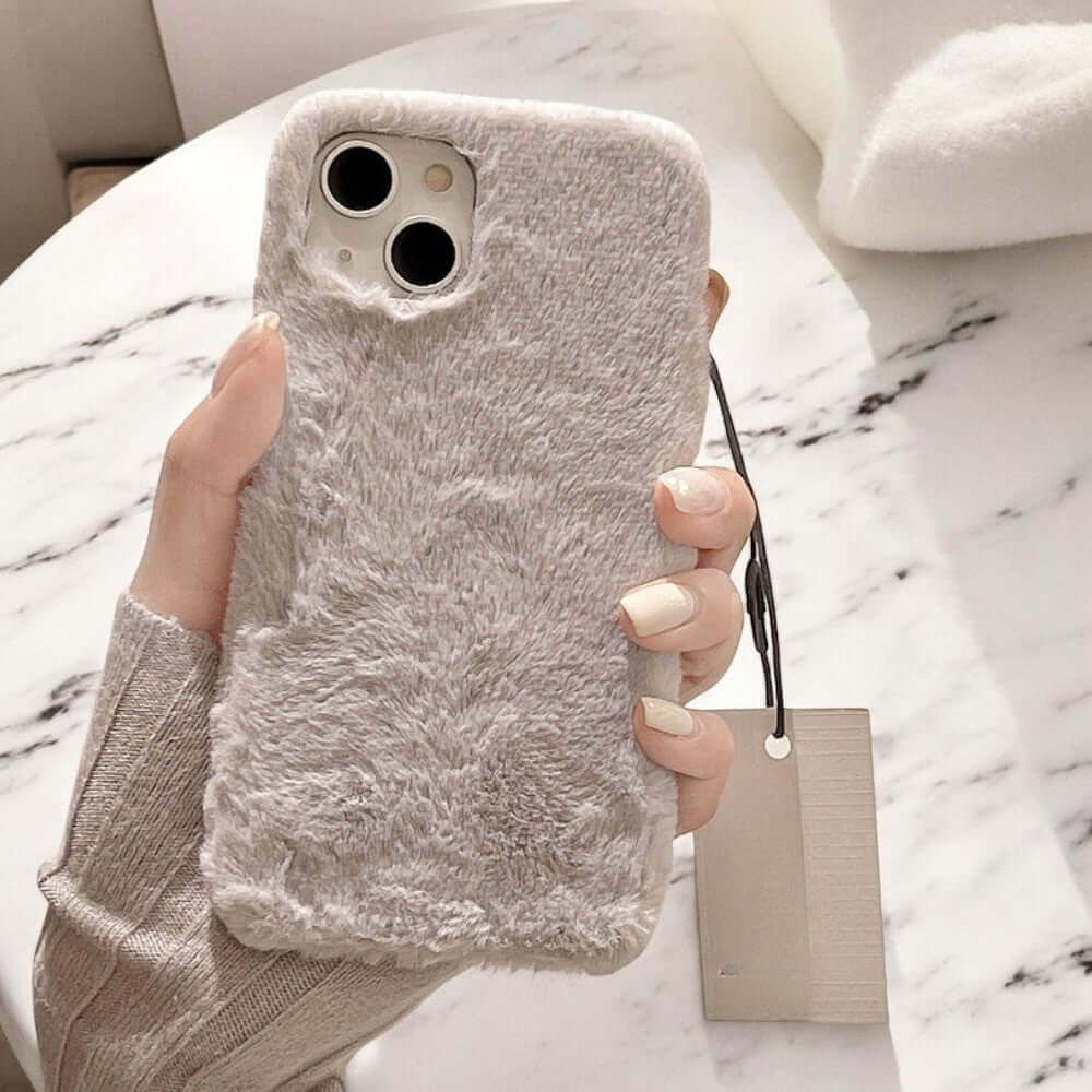 a woman holding up a phone case with a fuzzy design