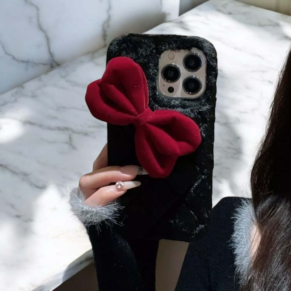 a woman holding a phone case with a red bow on it